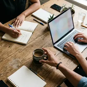 People taking notes around a wooden meeting table