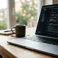 A laptop on a desk showing an editor with soft-focus lines of code