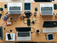 Overhead view of a shared desk covered in devices