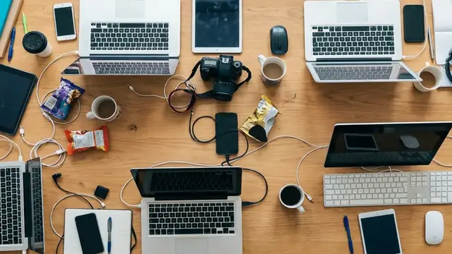 Overhead view of a shared desk covered in devices